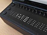 A closeup photograph of a refreshable Braille display showing the holes through which platic pins form the characters.